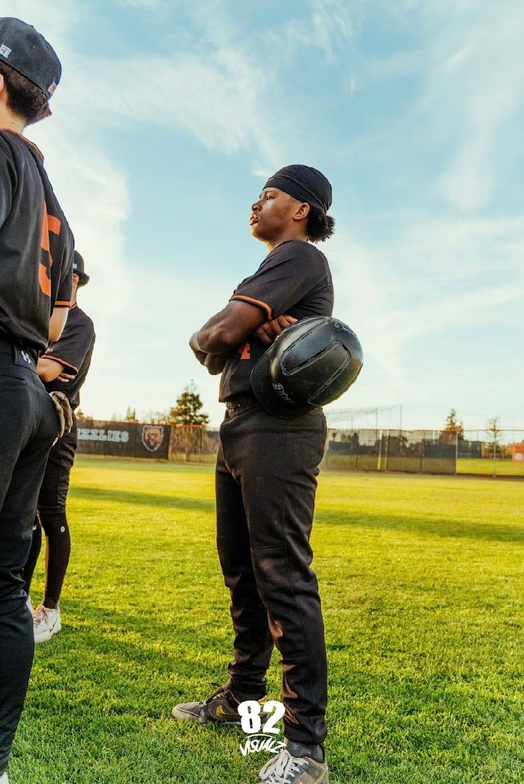 Kai Watts standing with his arms crossed, holding his helmet