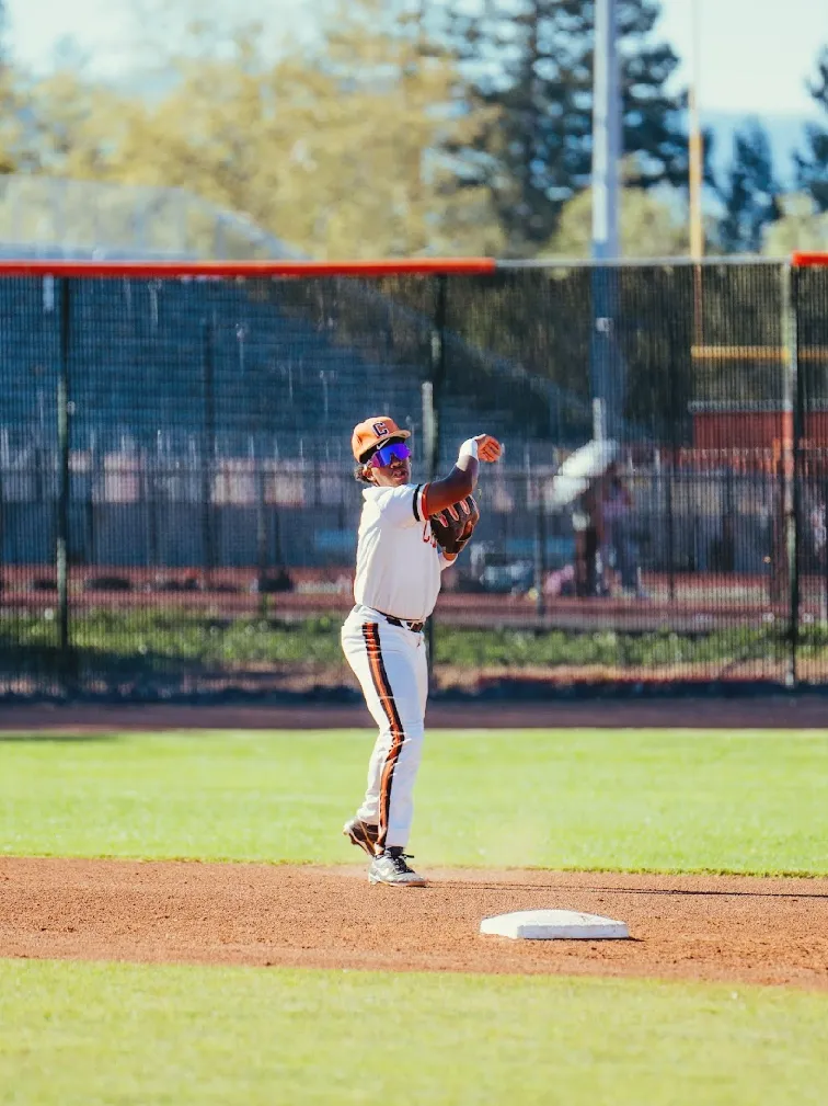 Kai Watts finishing a throw next to second base in the white home uniform